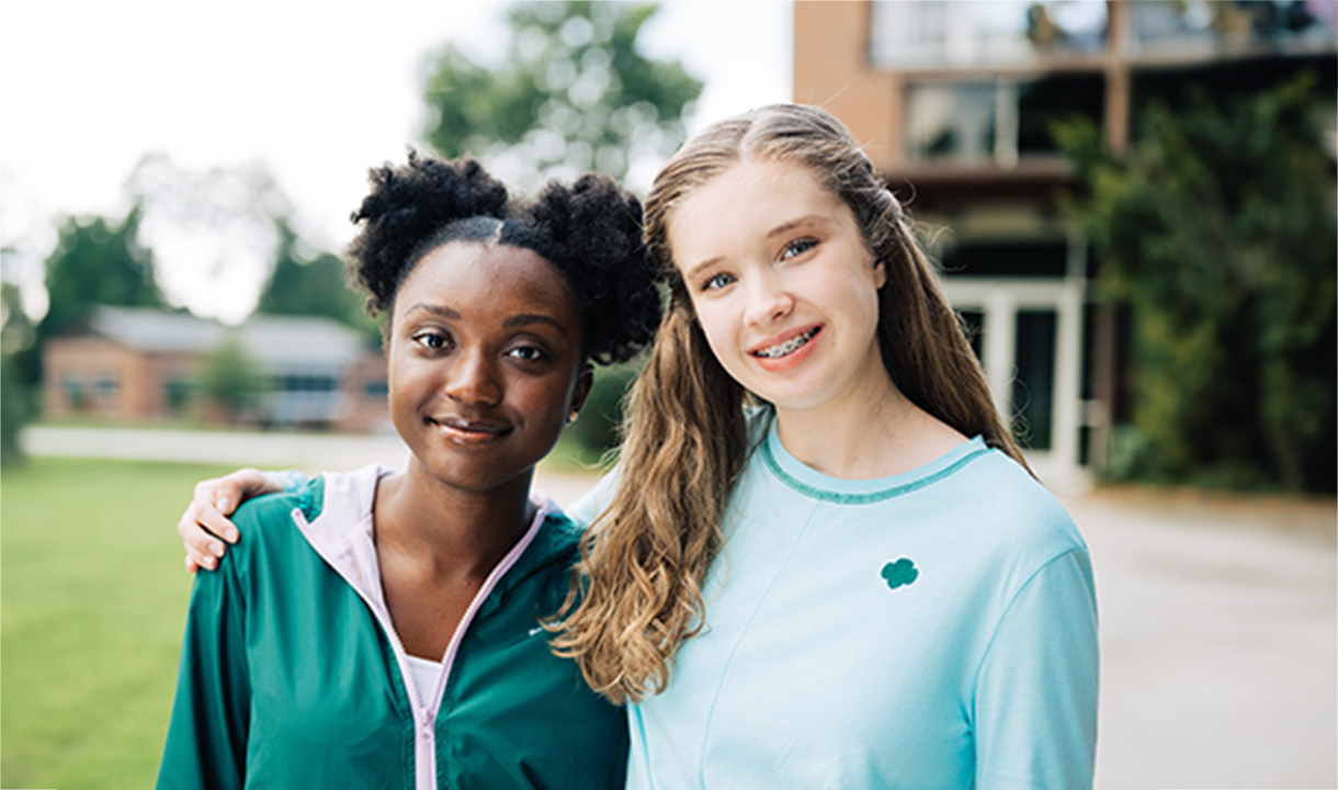 Two girls with their arms around each other's shoulders